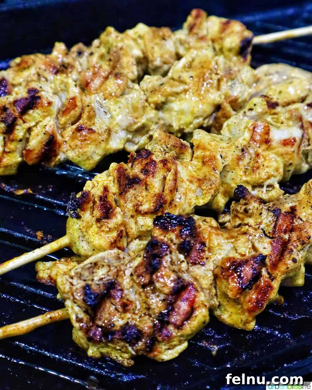 Spicy Peanut Glazed Chicken Skewers 9 Chicken skewers grilling outdoors on a barbecue, showing char marks.