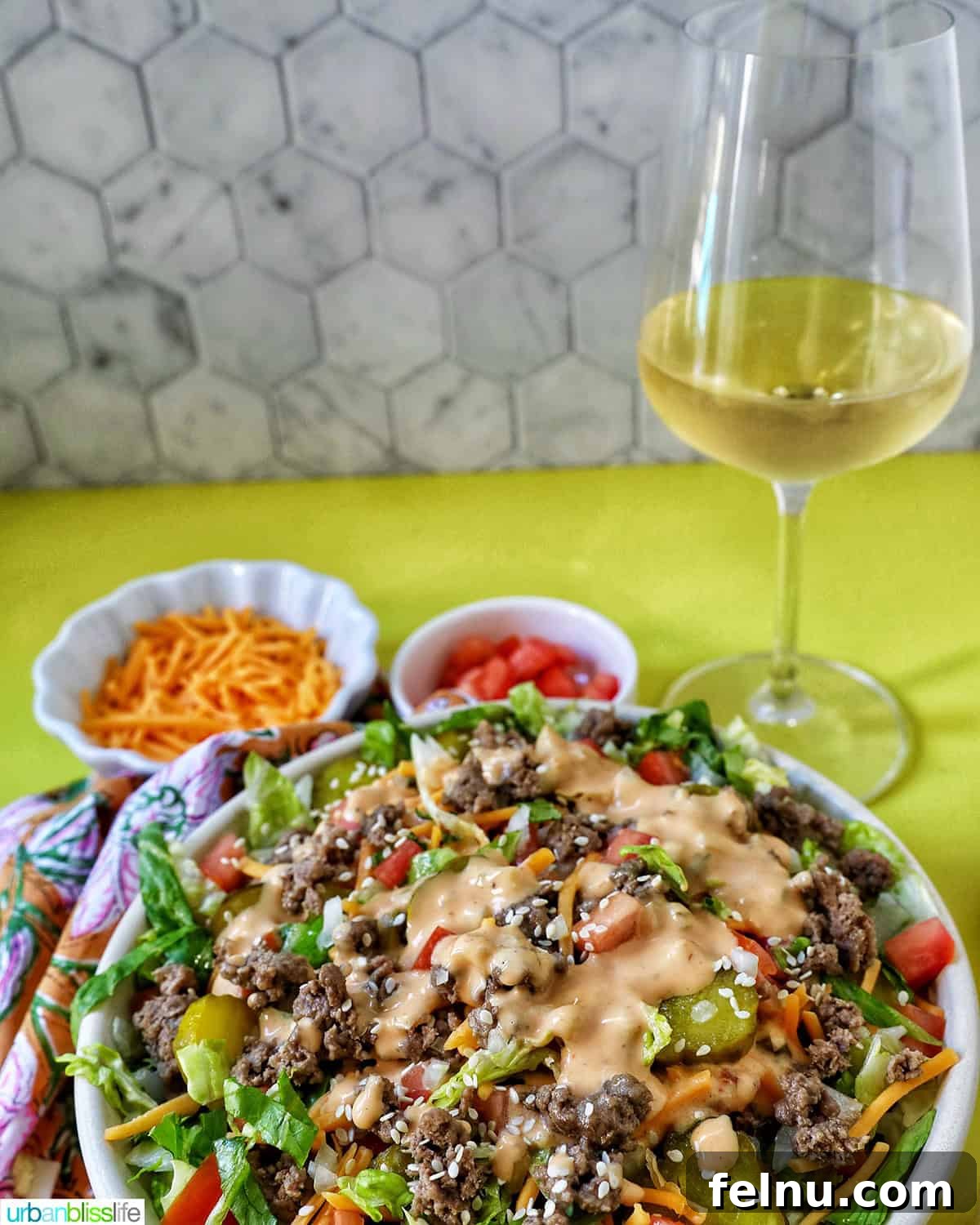 Big Mac Burger Bowl 16 Big Mac Salad in a bowl next to a glass of white wine, suggesting a elegant pairing.