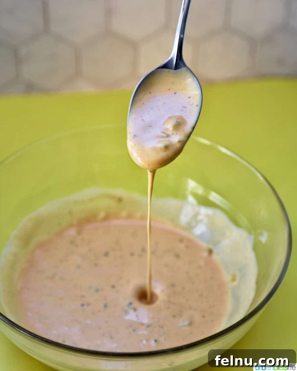 Big Mac Burger Bowl 8 A spoon dripping Big Mac sauce over a bowl of the prepared sauce, showing its creamy texture.