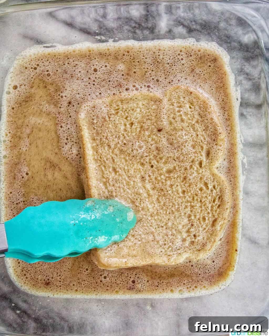 Power-Packed Protein French Toast 6 tongs dipping a slice of bread into high protein french toast batter.