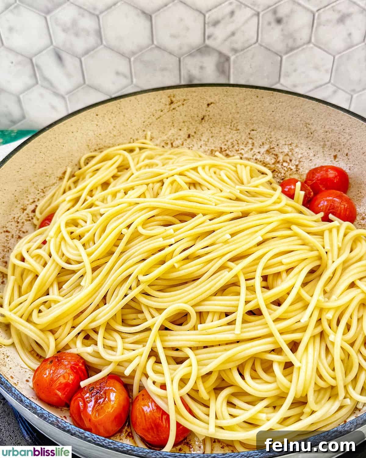 Vibrant Cherry Tomato Pesto Pasta 7 spaghetti pasta with cherry tomatoes in a pan.