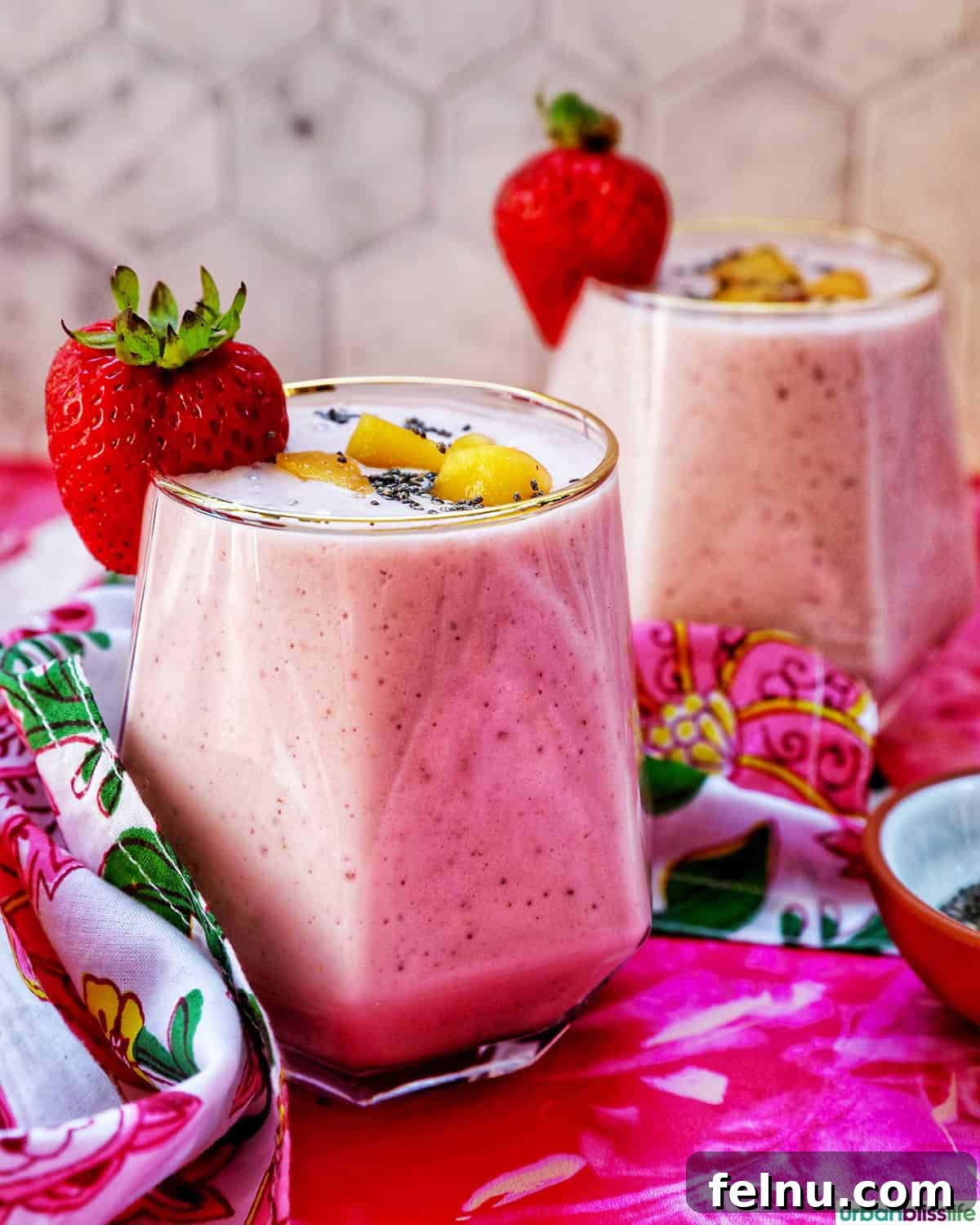 Peachy Berry Bliss 3 Two glasses of strawberry peach smoothie, garnished, with colorful napkins and a side bowl of chia seeds.