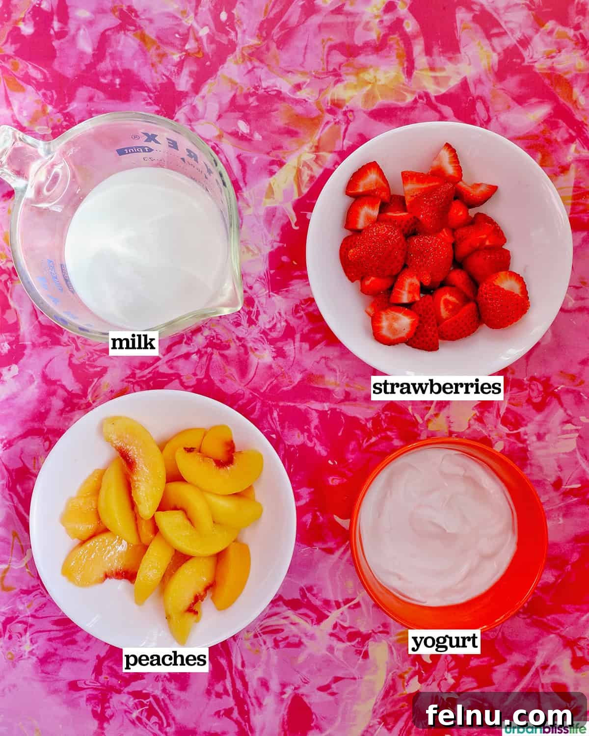Peachy Berry Bliss 4 Bowls of milk, quartered strawberries, sliced peaches, and plain Greek yogurt arranged on a colorful pink background, showcasing the fresh ingredients for the smoothie.