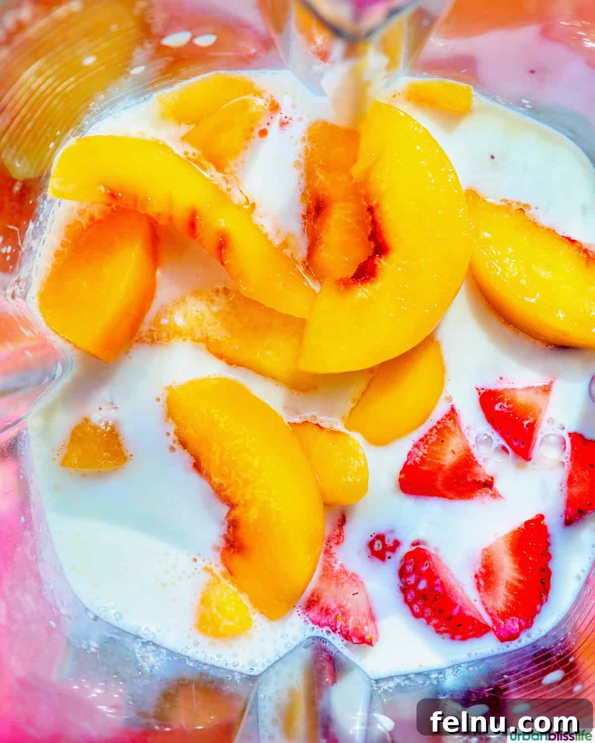 Peachy Berry Bliss 6 Sliced peaches, quartered strawberries, milk, and a scoop of Greek yogurt added to a blender, ready for blending.