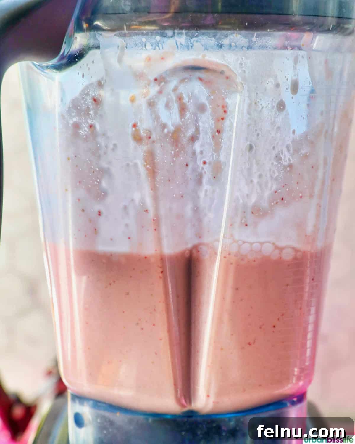 Peachy Berry Bliss 7 The strawberry peach smoothie actively blending in a high-powered blender, showing a smooth, creamy texture forming.