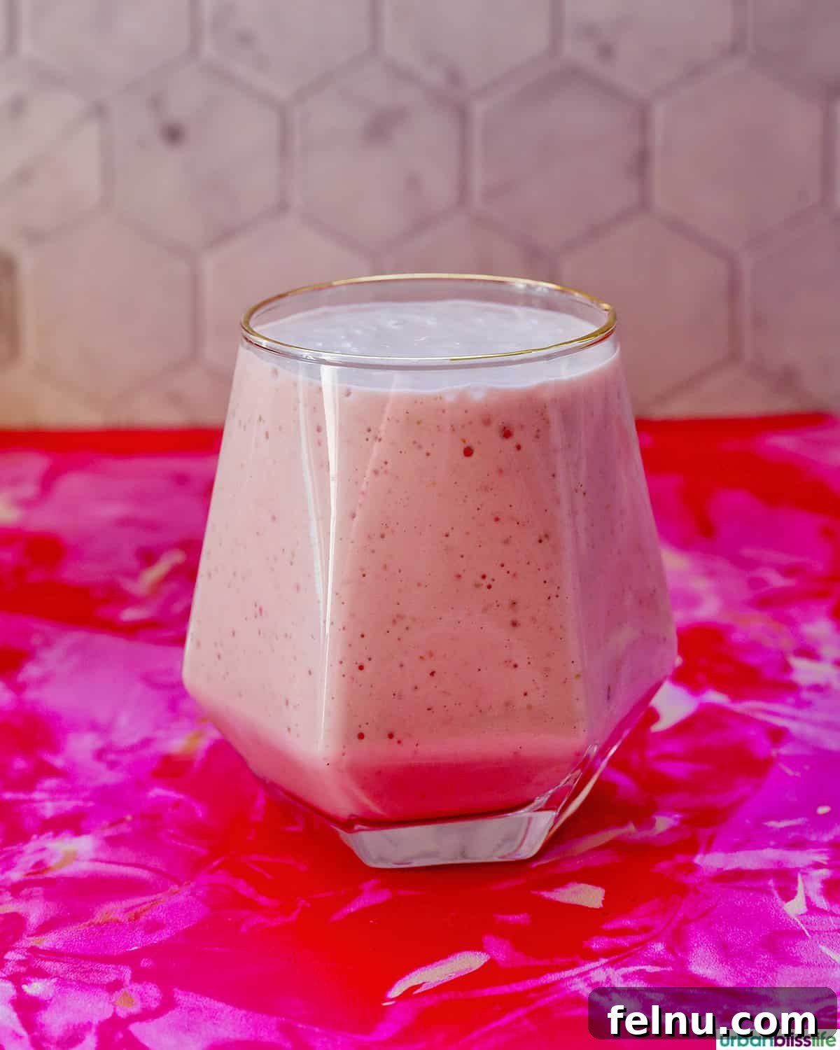 Peachy Berry Bliss 9 A freshly poured glass of strawberry peach smoothie, showcasing its smooth texture and vibrant color, ready to be garnished.