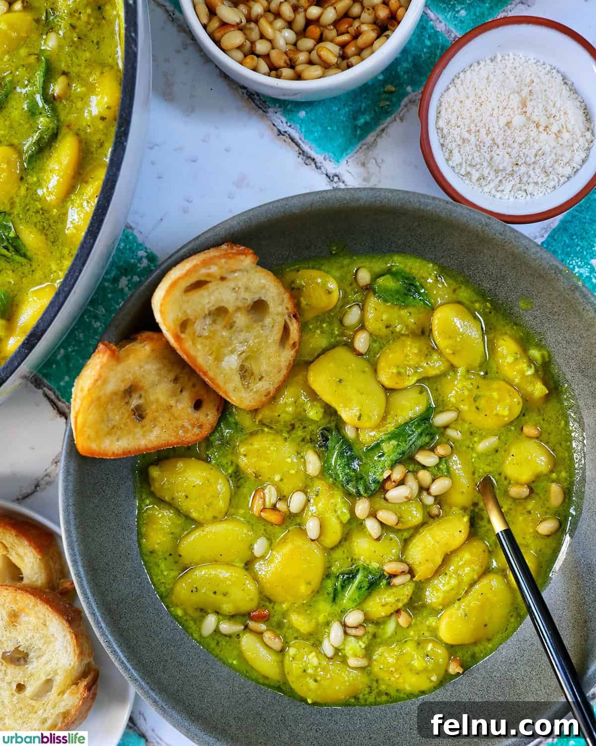 bowl of pesto beans with crostini slices and side bowls of parmesan cheese and pine nuts.