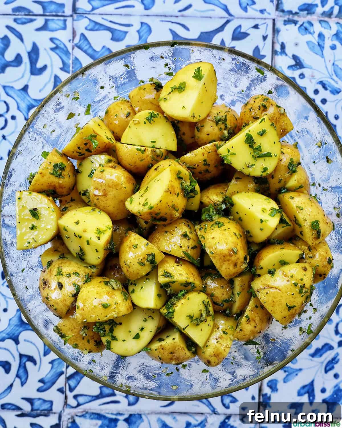 Potatoes being tossed with herbs and olive oil.