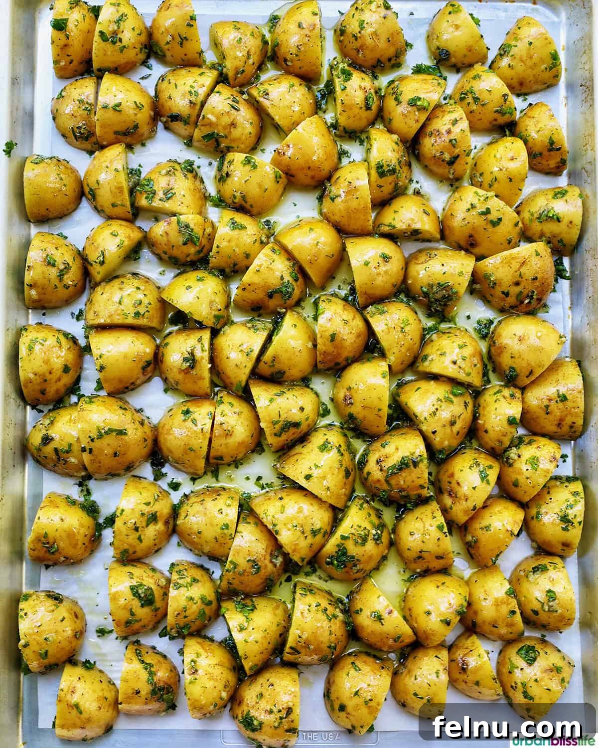 Herby potatoes arranged on a baking sheet.