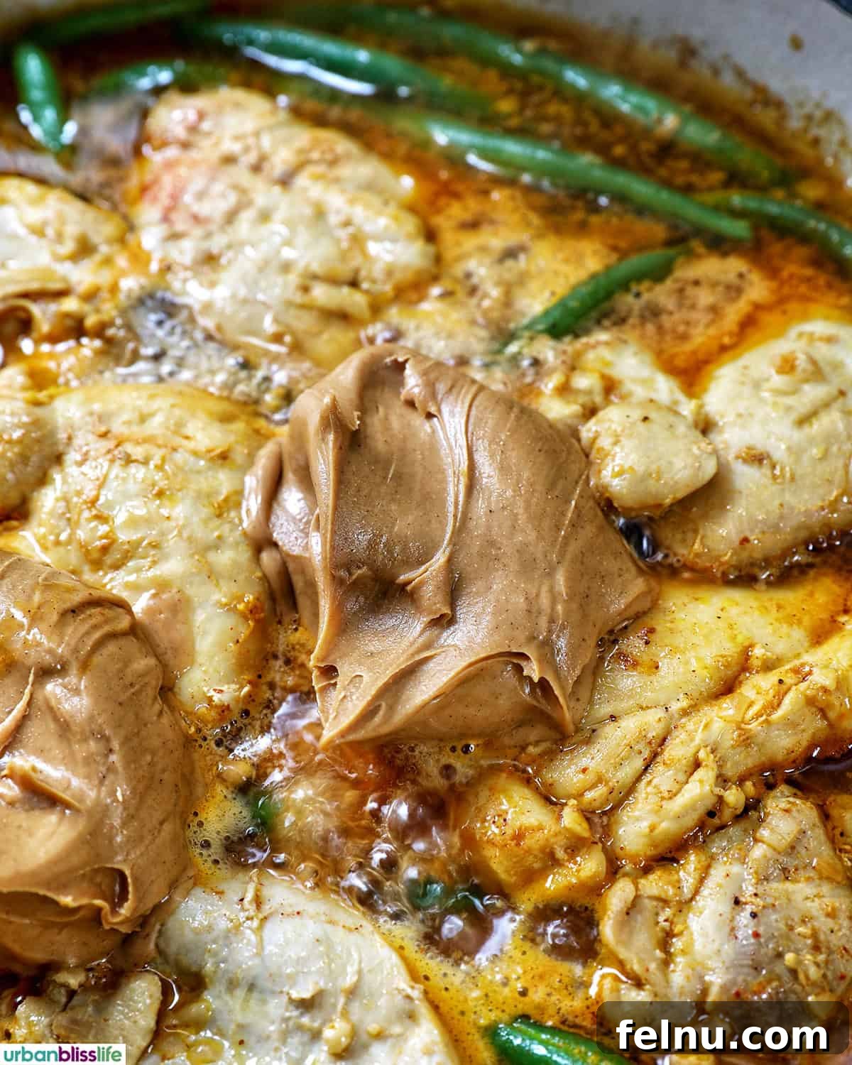 Rich Filipino Peanut Chicken 14 Creamy peanut butter being stirred into the chicken kare kare stew.