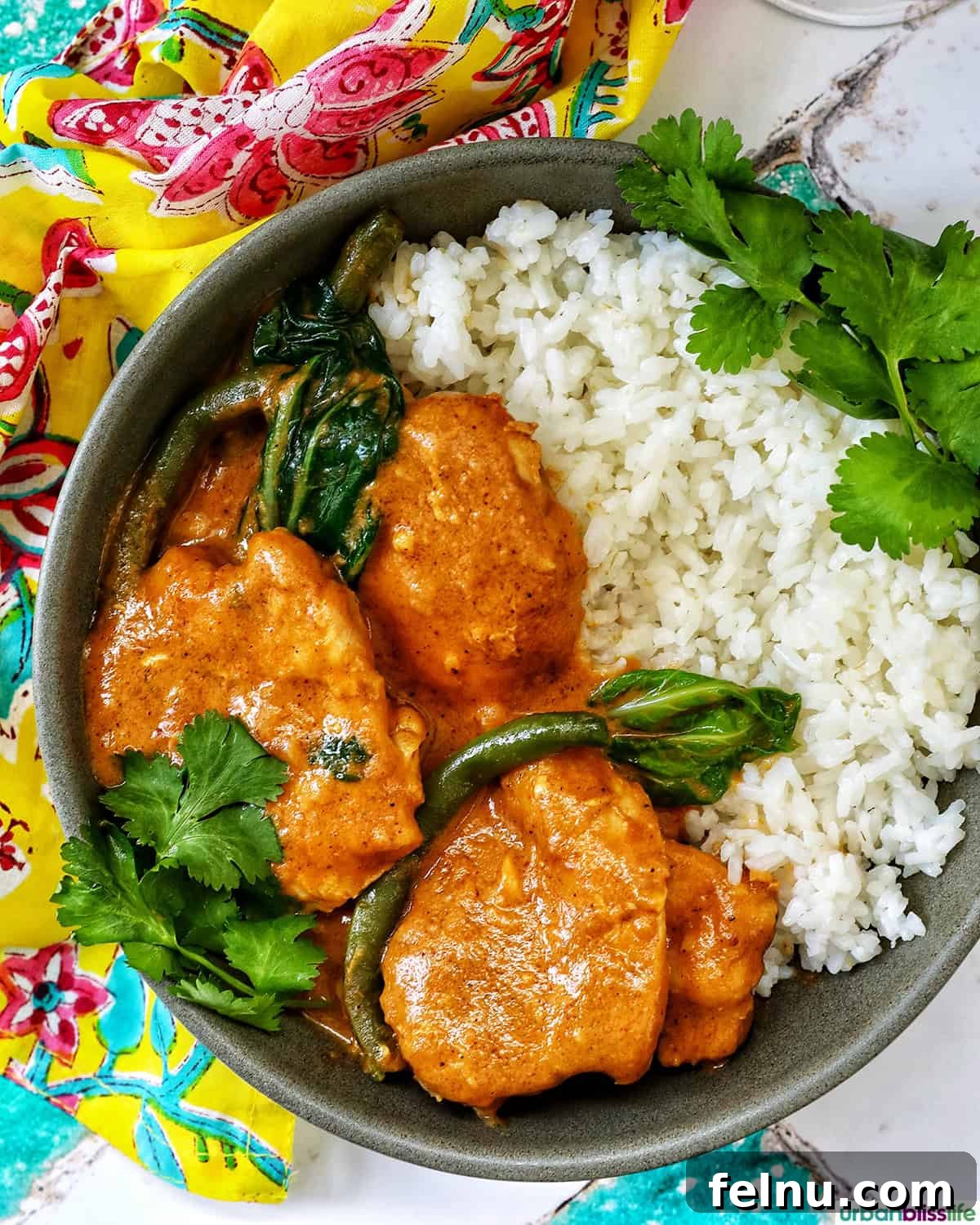 Rich Filipino Peanut Chicken 18 A beautifully presented bowl of Filipino chicken kare kare, garnished with a lime wedge and served with rice.