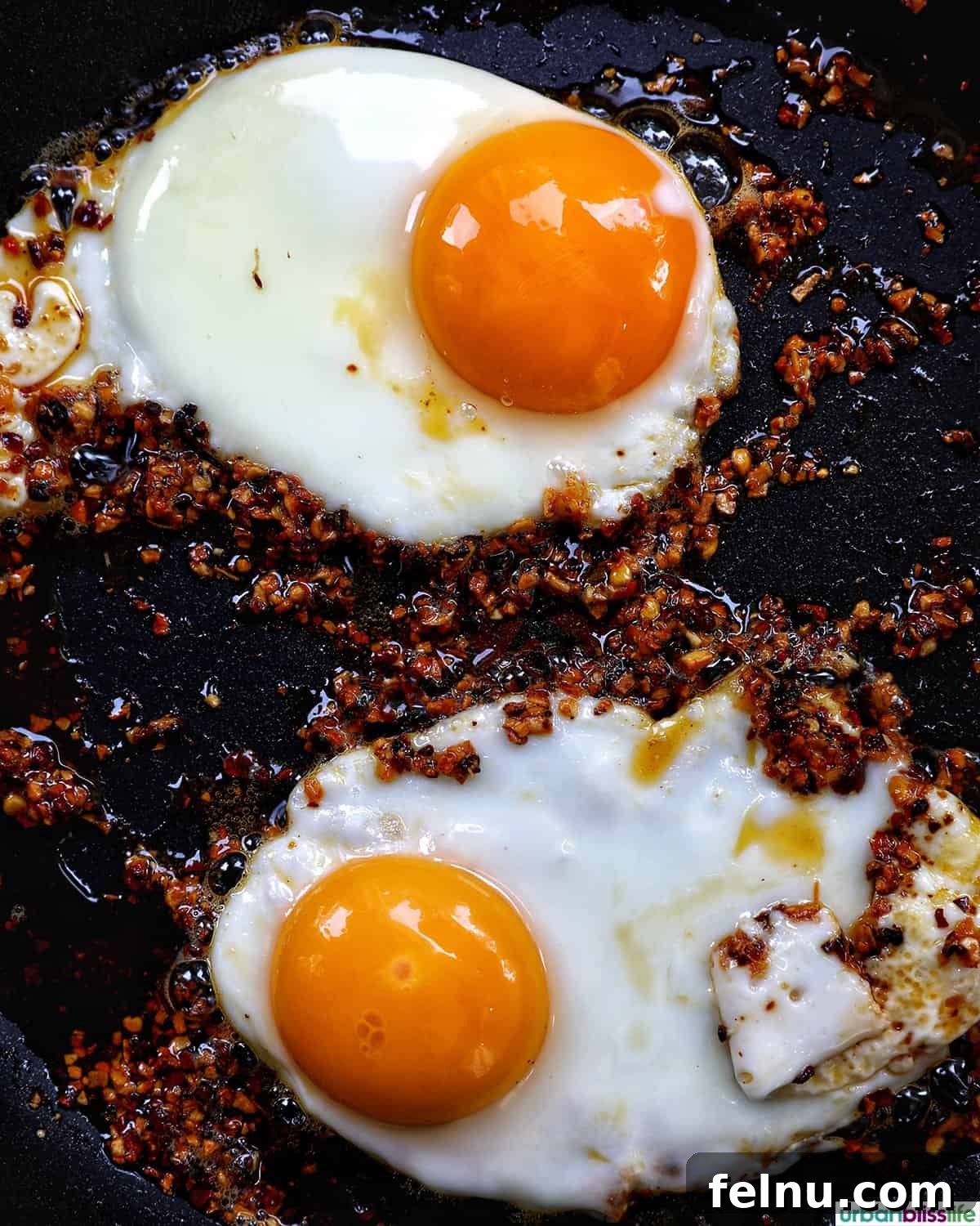 Golden Yolks, Fiery Crunch 8 Chili crisp eggs cooking in the pan, whites set and yolks still runny.