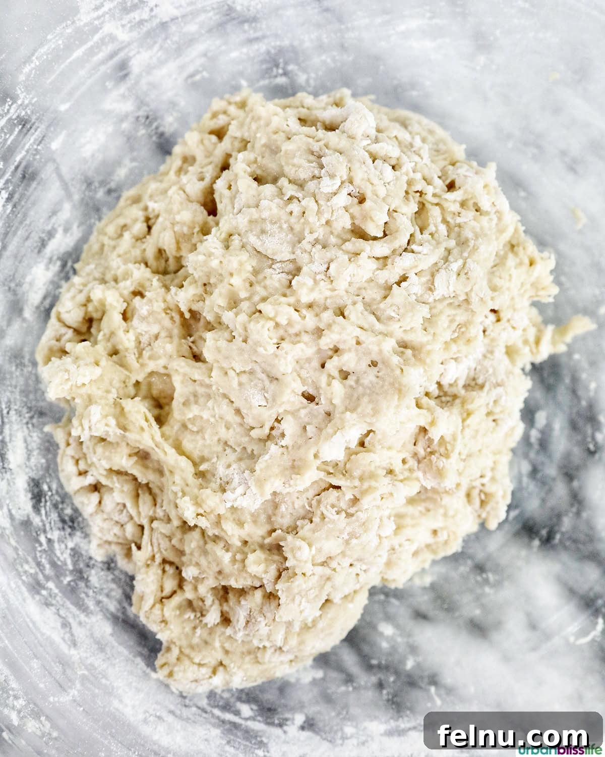 Smooth cinnamon roll dough forming in a mixing bowl.
