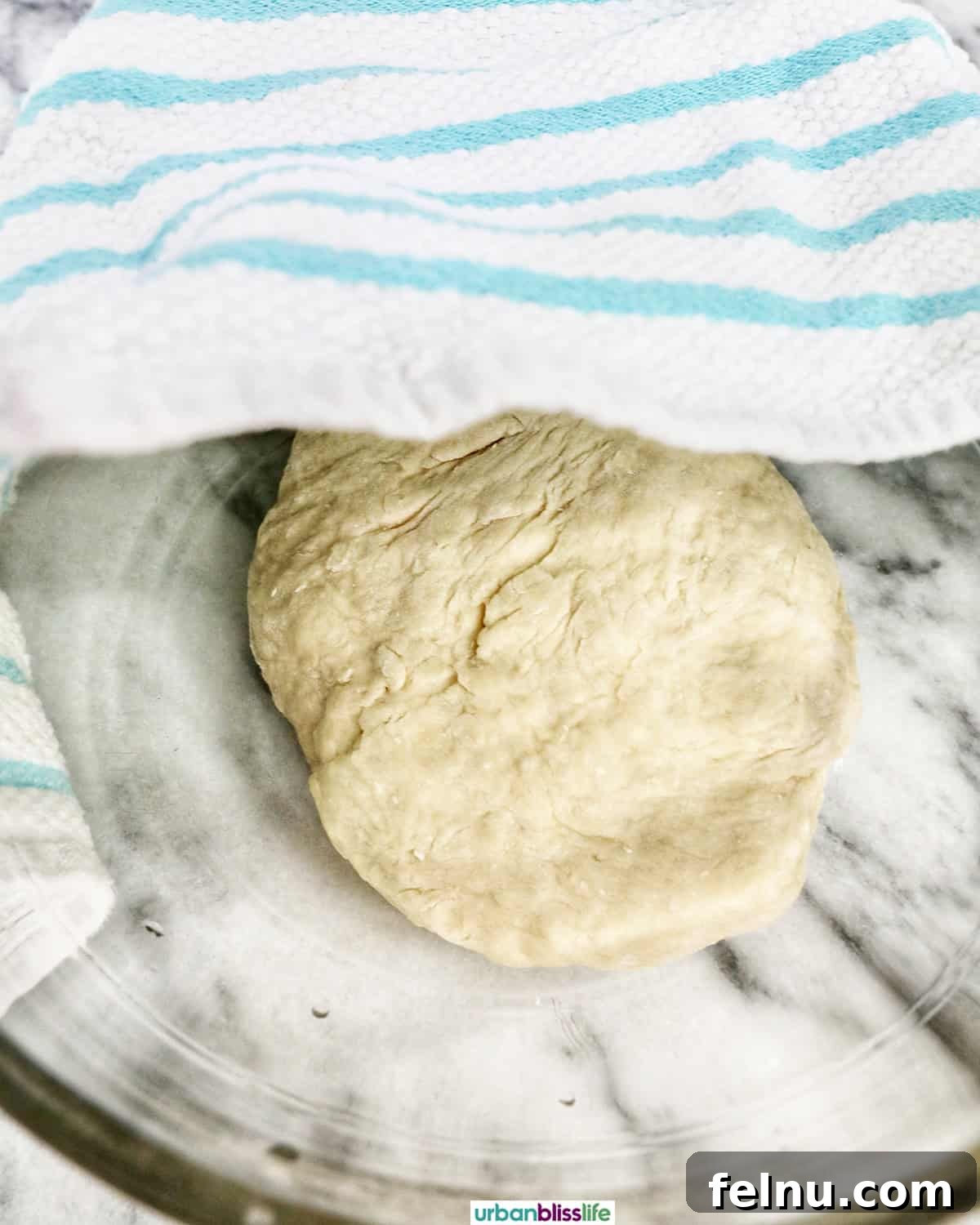 Dough resting in a bowl, covered with a towel for its first rise.