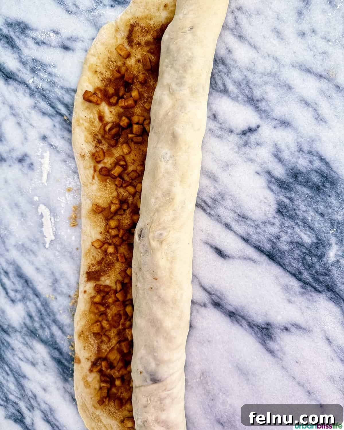 Apple pie cinnamon roll dough tightly rolled into a log.