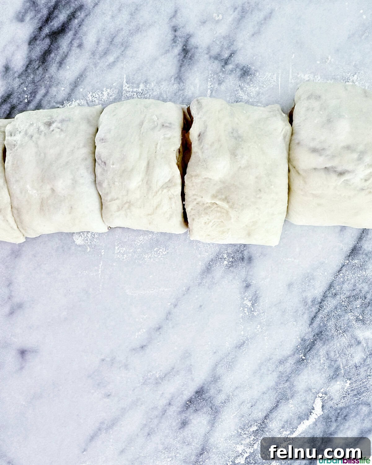 Cinnamon roll log sliced into individual rolls before baking.