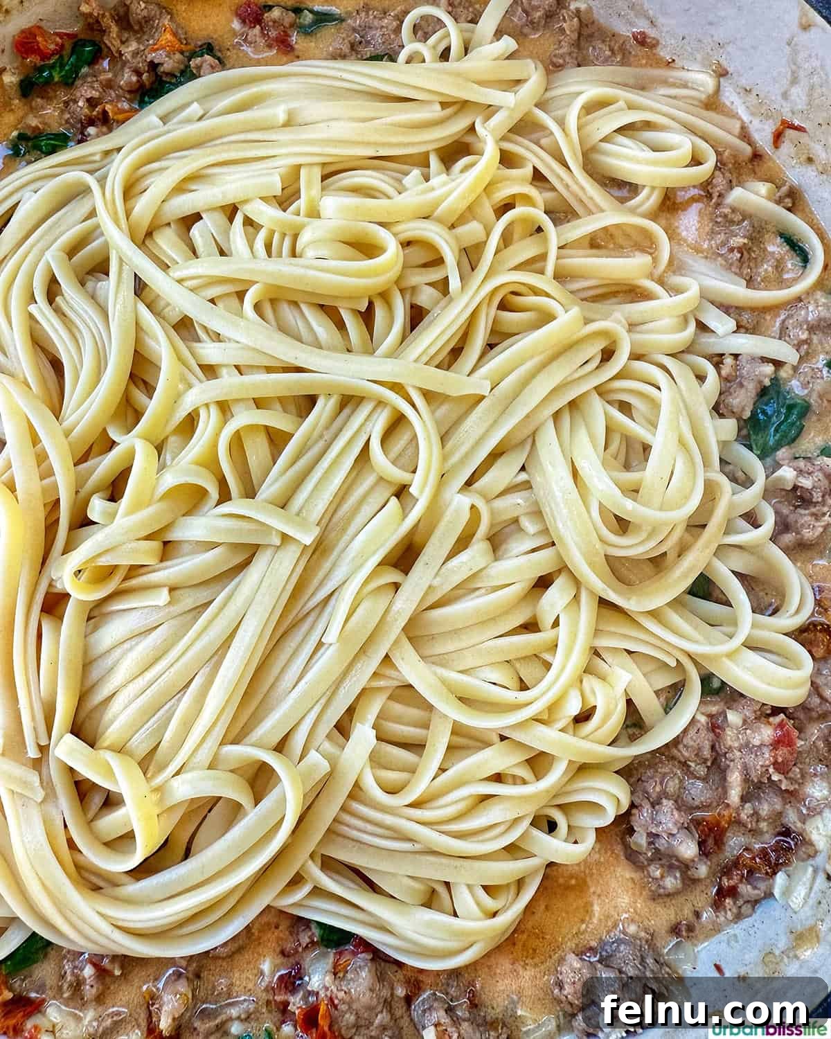 Tuscan Sausage Pasta Delight 17 Cooked pasta in a skillet with meat sauce