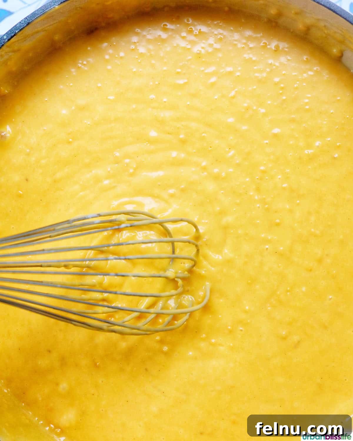 Fully melted, smooth, and creamy cheese sauce shimmering in the pan, ready for spices.