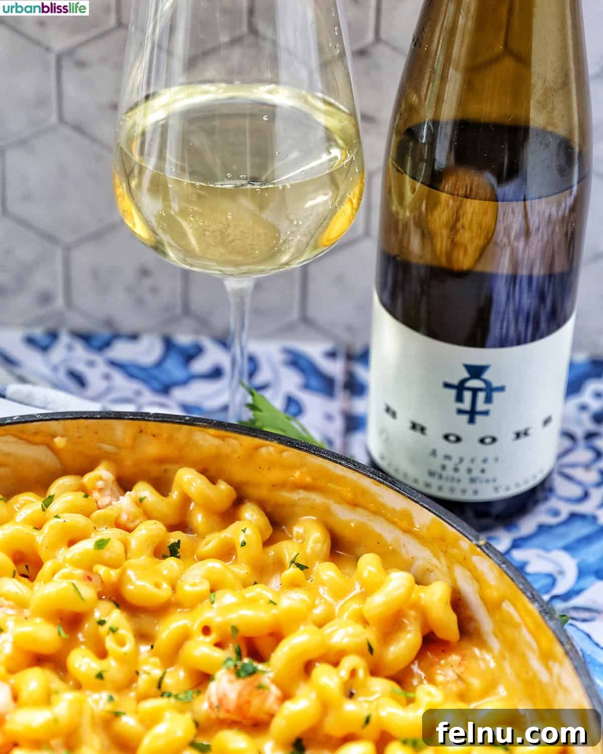 A beautiful serving of lobster mac and cheese, perfectly complemented by a glass of crisp white wine.