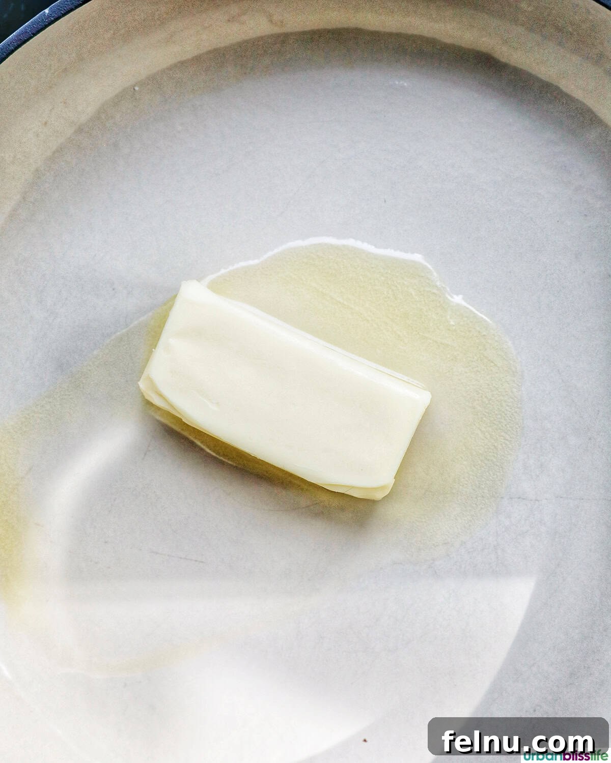 A stick of vegan butter placed in a large white skillet, ready for melting.