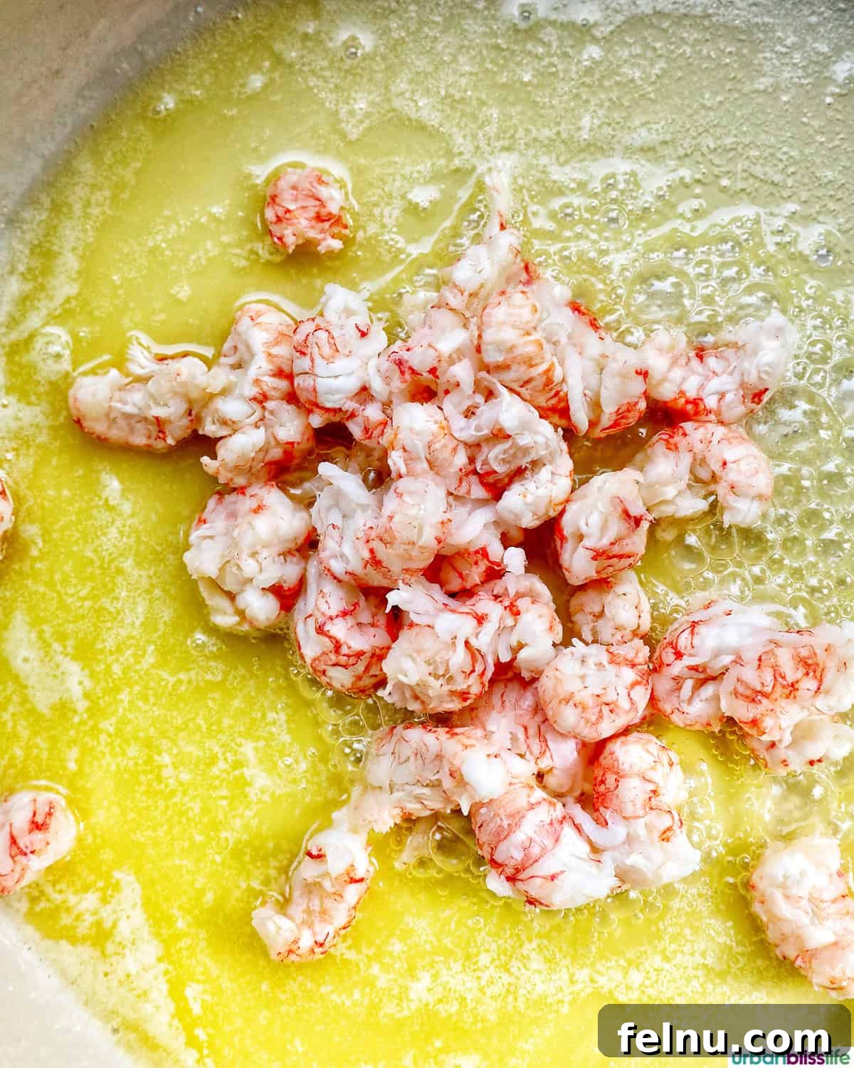 Chunks of cooked lobster meat being lightly sautéed in melted butter within a large skillet, developing flavor.
