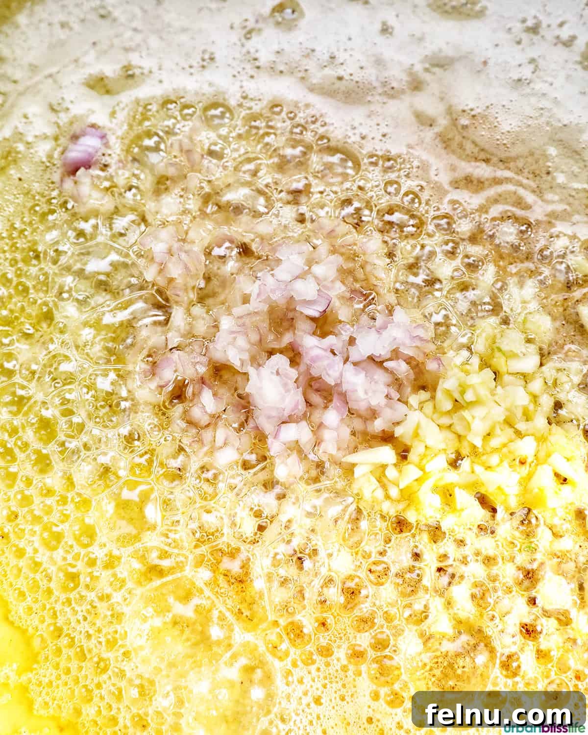 Finely minced shallots and garlic sizzling gently in melted butter within a pan.