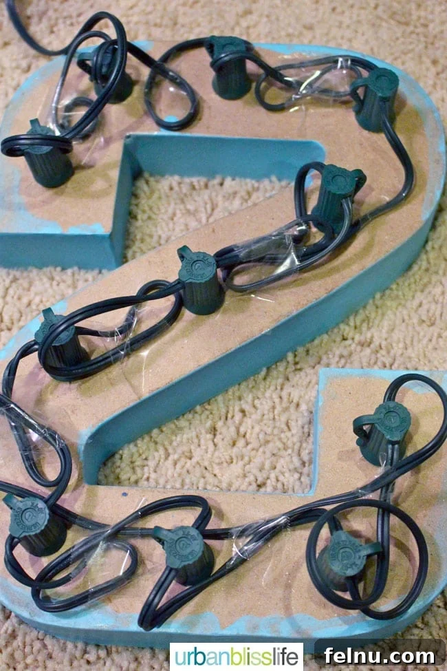Simple DIY Illuminated Signage Guide 12 Taping down the light strings on the back of the paper mache letters