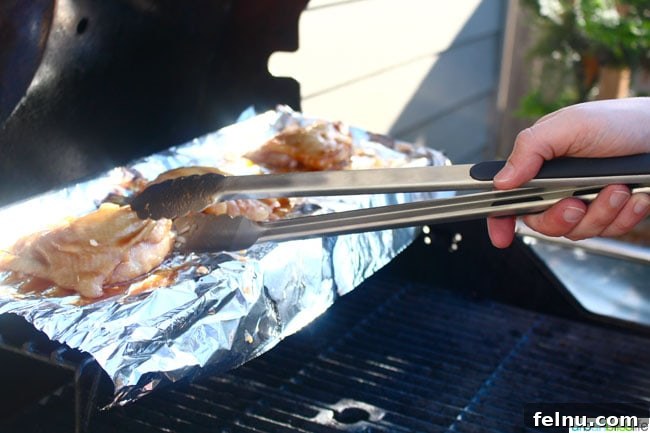 Ginger-Infused Grilled Chicken with Apple Cider Glaze 5 Close-up shot of Cider Ginger Grilled Chicken being flipped on the grill using tongs, showcasing the grilling process.