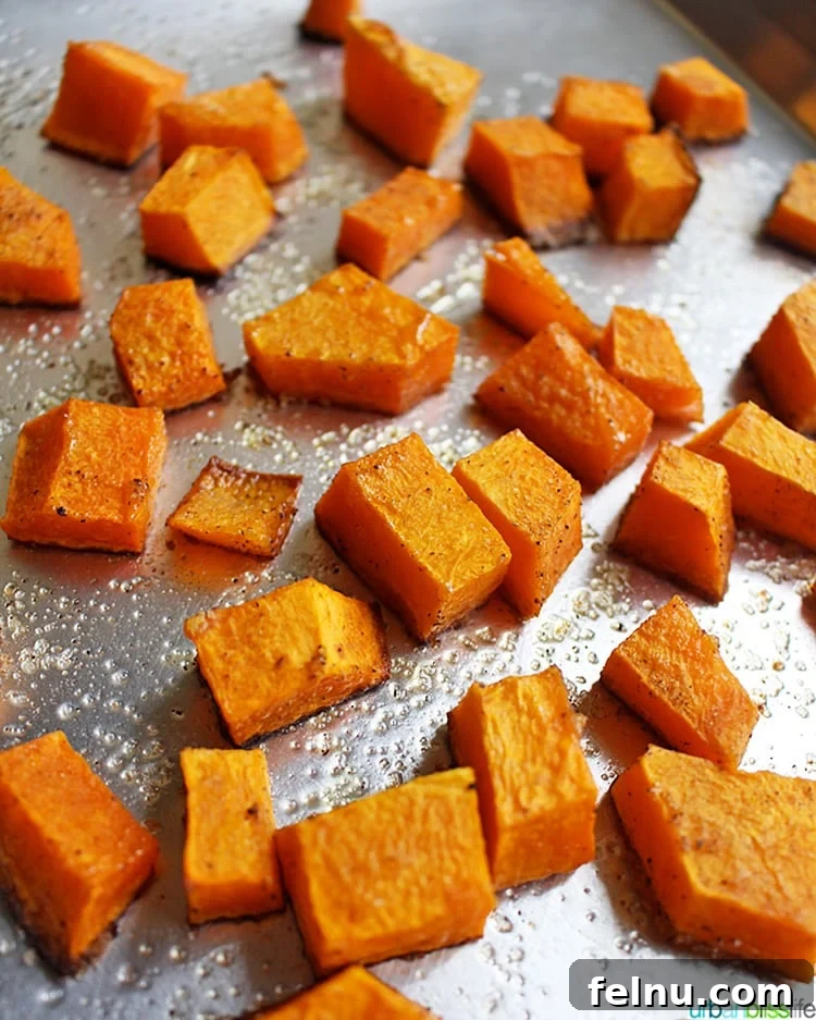 Butternut squash cubes spread out on a roasting pan, ready for cooking