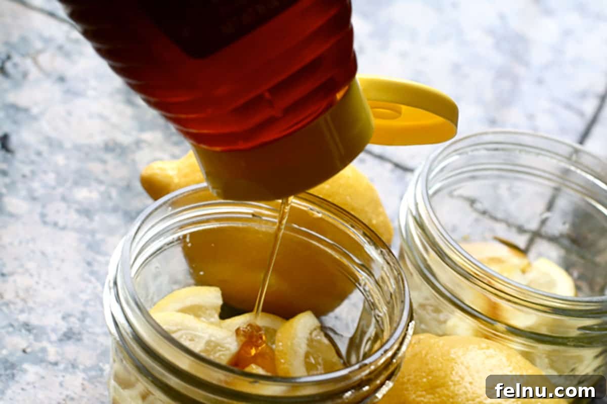 Pouring honey into a mason jar containing lemon wedges