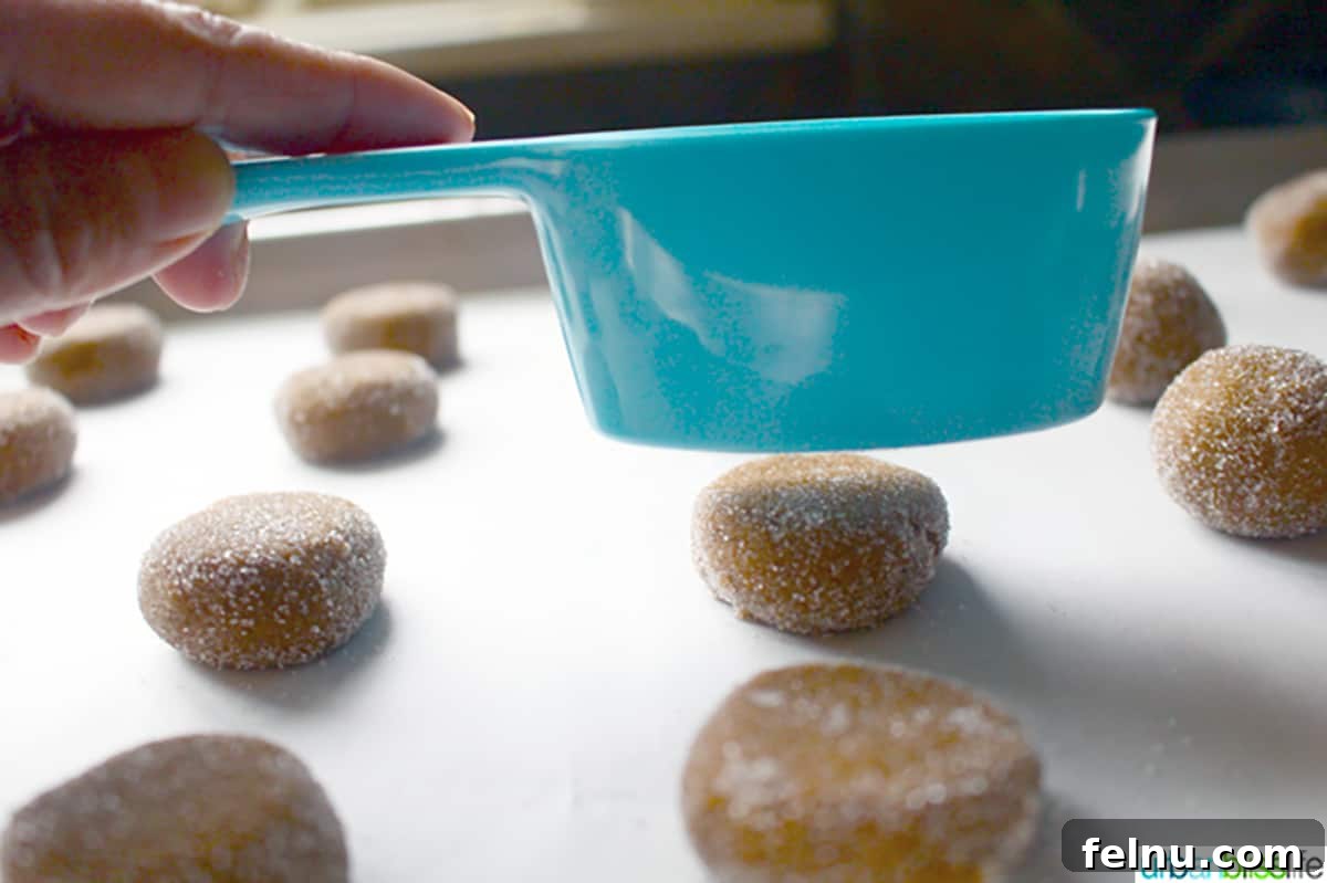Chewy Ginger Molasses Cookies Gingersnap Delights: Soft & Chewy Molasses Cookies 10 Tapping down on ginger molasses cookies with a measuring cup