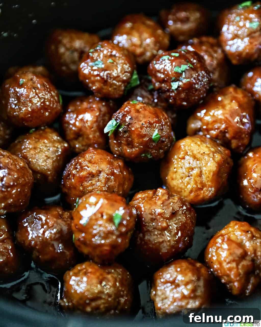 Honey Bourbon Glazed Meatballs (Slow Cooker Recipe) 11 Honey bourbon meatballs garnished with parsley in a slow cooker.