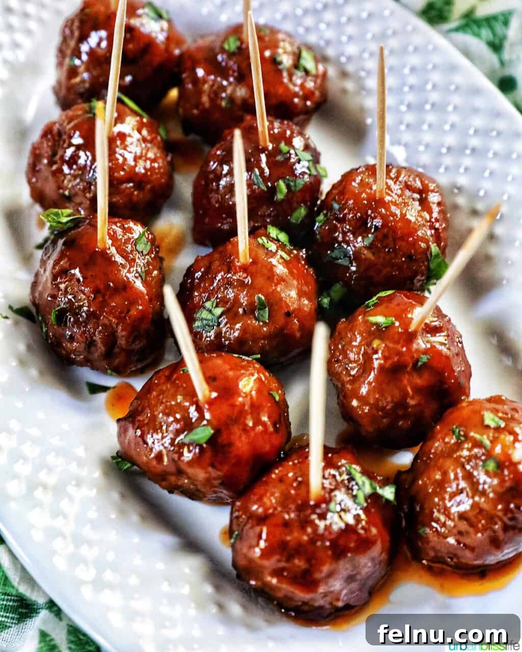 Honey Bourbon Glazed Meatballs (Slow Cooker Recipe) 3 Honey bourbon meatball appetizers on a white serving plate.