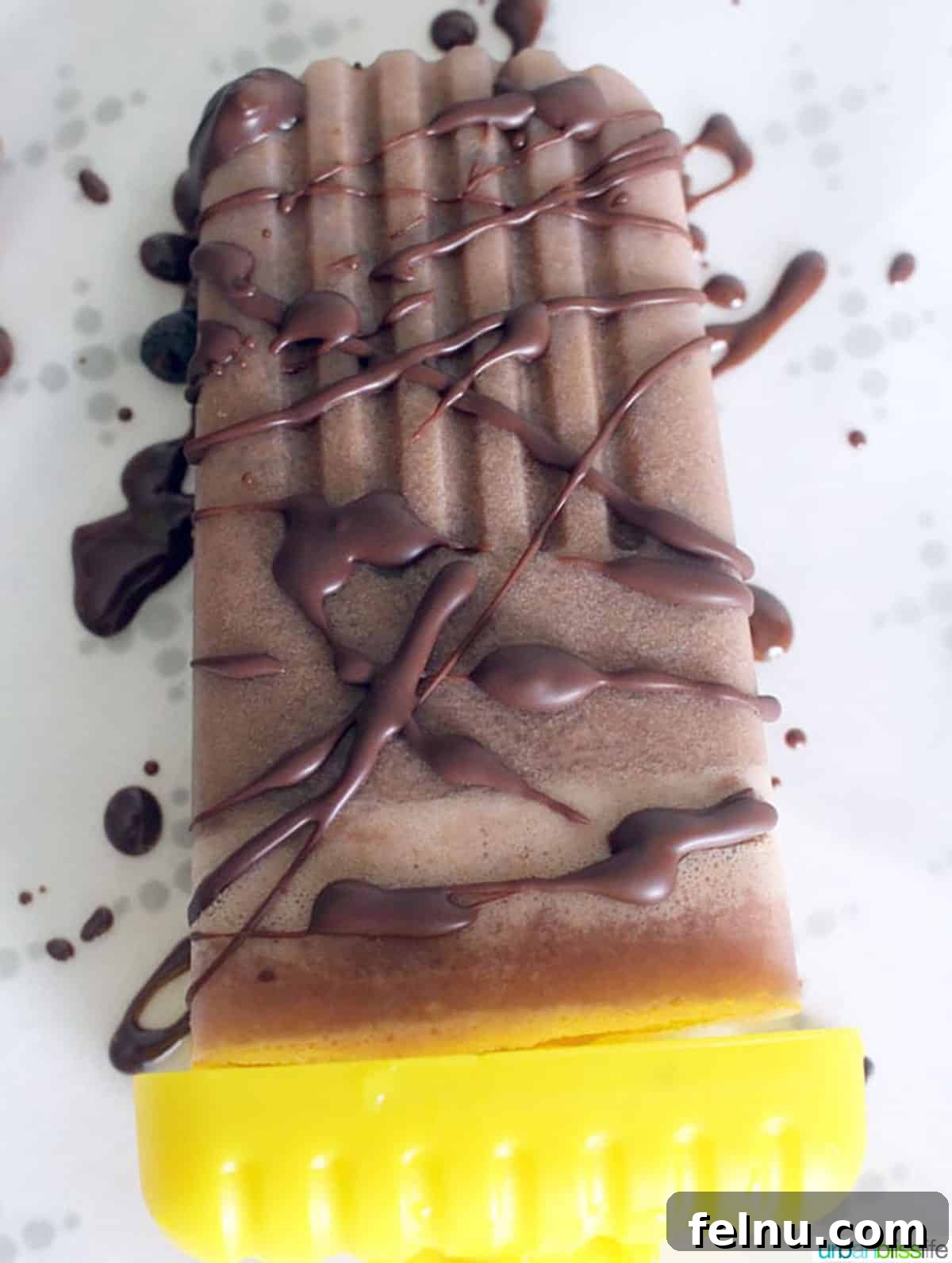 Plant-Based Chocolate Peanut Butter Fudge Pops with Chocolate Chunks 3 Close-up of a perfectly drizzled chocolate peanut butter popsicle, highlighting its rich texture.
