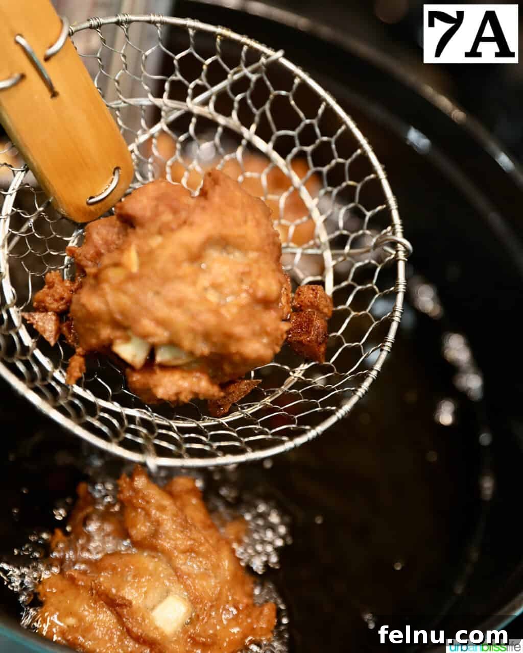 Crispy Cinnamon Apple Fritters 14 A cooking spider lifting a golden brown apple fritter donut from the hot oil.