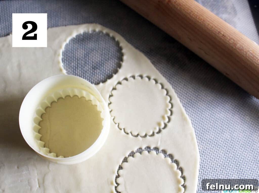 Golden Pear Bites 4 Pre-made pie dough rolled out on a floured surface, with round shapes being cut out using a circular cookie cutter, ready for individual tartlet bases.