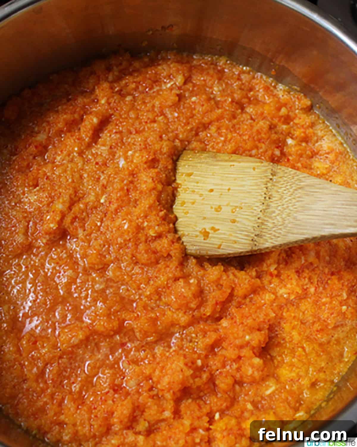 Sweet and Spicy Chili Dip 5 Sweet chili dipping sauce simmering in a pan, being gently stirred with a wooden spoon, illustrating the cooking process.