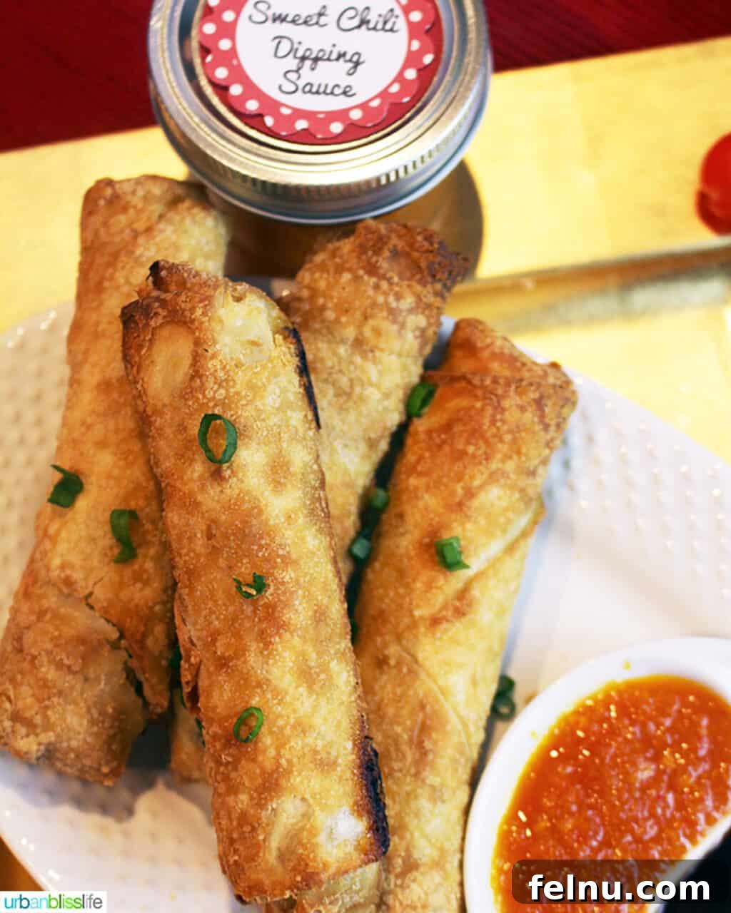 Sweet and Spicy Chili Dip 7 Sweet chili dipping sauce served in a small bowl, perfectly paired with crispy, golden brown egg rolls stacked nearby.