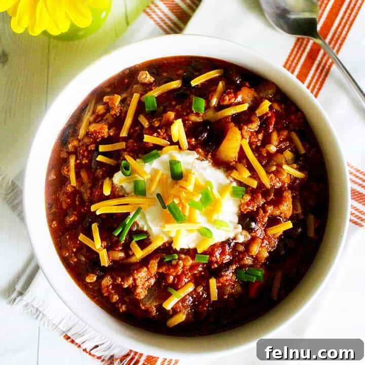 A delicious bowl of turkey chili with ground turkey, farro, and stout, beautifully presented with a medley of toppings, inviting a warm and comforting meal.