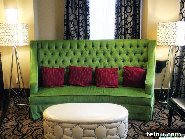 A plush green couch in the lobby of The Maxwell Hotel Seattle, inviting guests to relax and unwind.