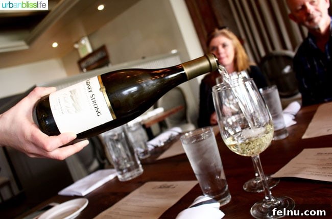 Rodney Strong Vineyards Your Sonoma Wine Escape 7 White wine pouring into a glass at Catelli's, with people in background