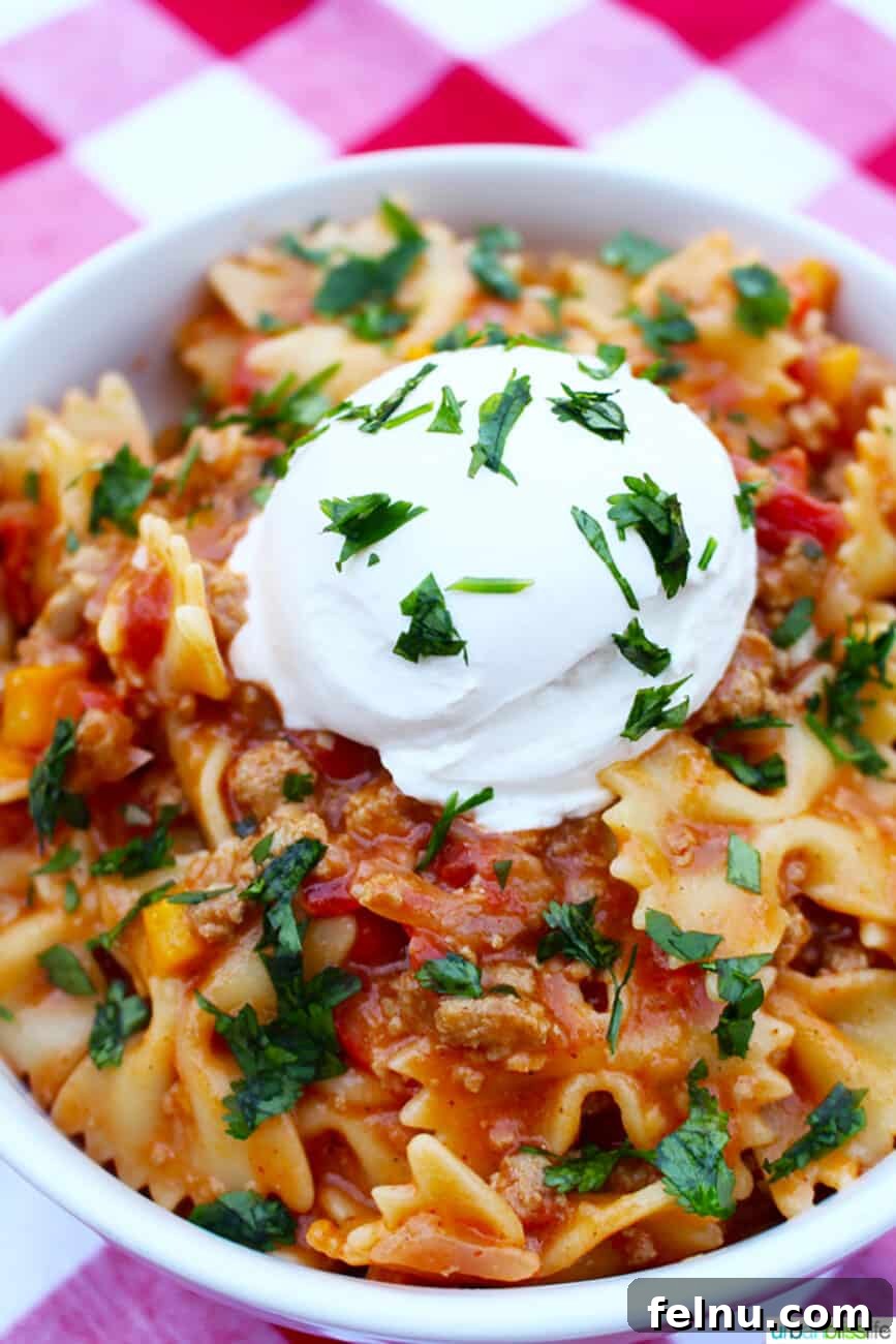 Close-up of Taco Pasta in a white bowl on a red and white checkered tablecloth