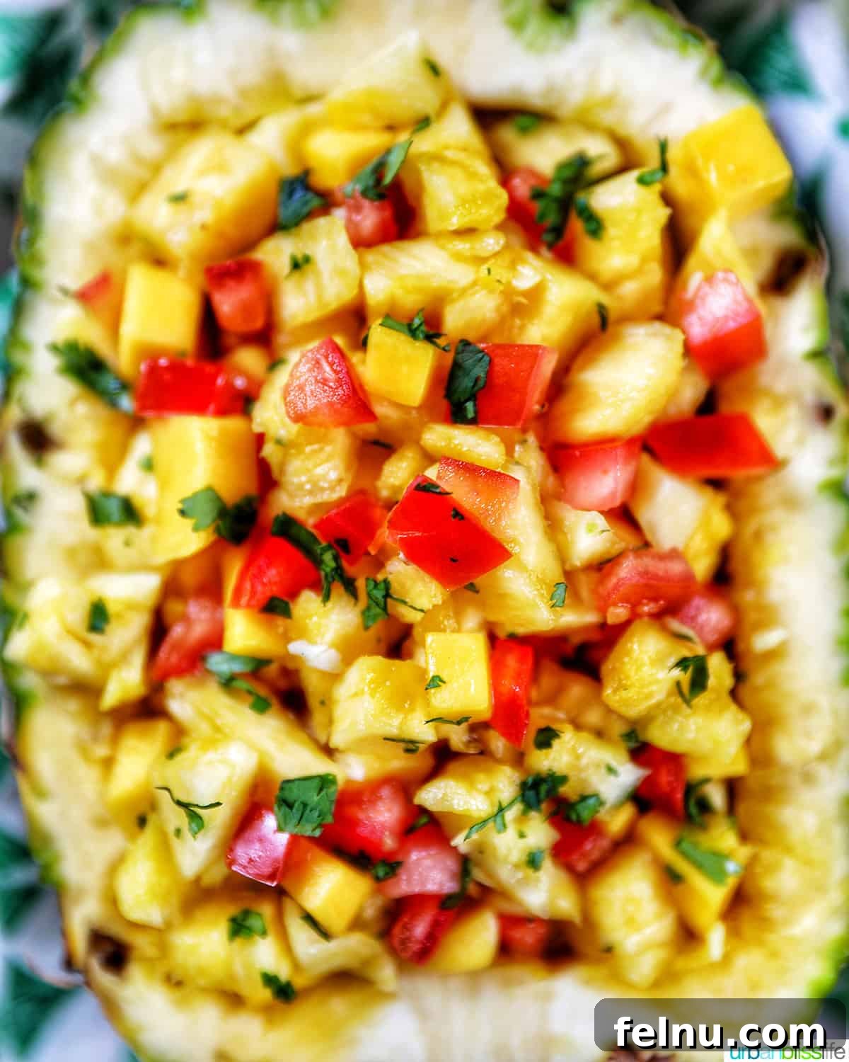 Sun-Kissed Fruit Salsa 2 A close-up shot of freshly chopped pineapple, mango, tomatoes, and onions, vibrant with tropical colors, artfully arranged in a hollowed-out pineapple shell, ready to be served.