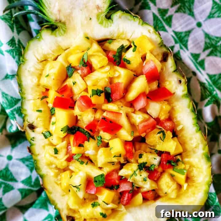 A vibrant pineapple mango salsa artfully presented in a hollowed-out pineapple shell, indicating a fresh and tropical dish.