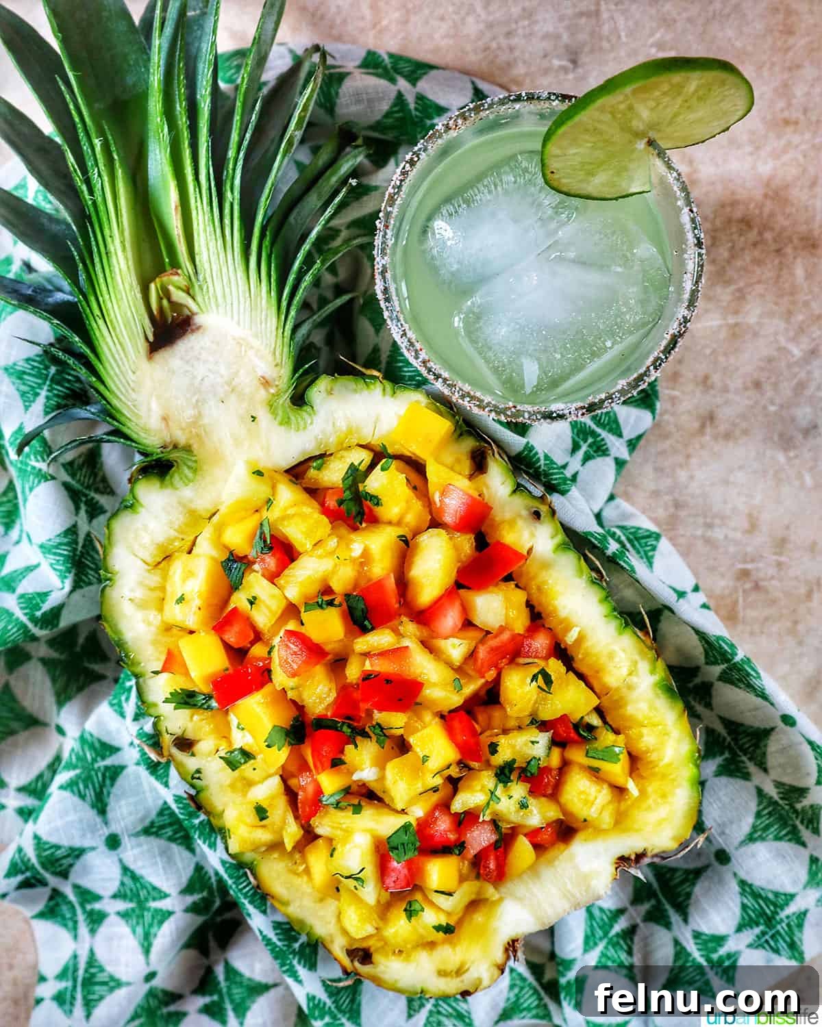 Sun-Kissed Fruit Salsa 8 A refreshing margarita in a salt-rimmed glass stands beside a hollowed-out pineapple filled with vibrant pineapple mango salsa, a perfect summer pairing.