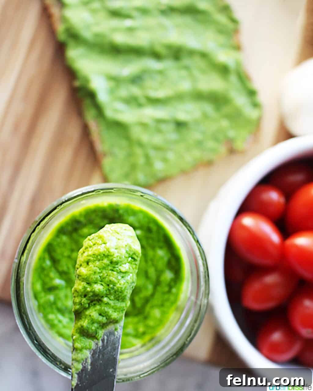 Creamy Avocado Pesto 8 bright green avocado pesto in a mason jar with a small knife placed in the pesto.