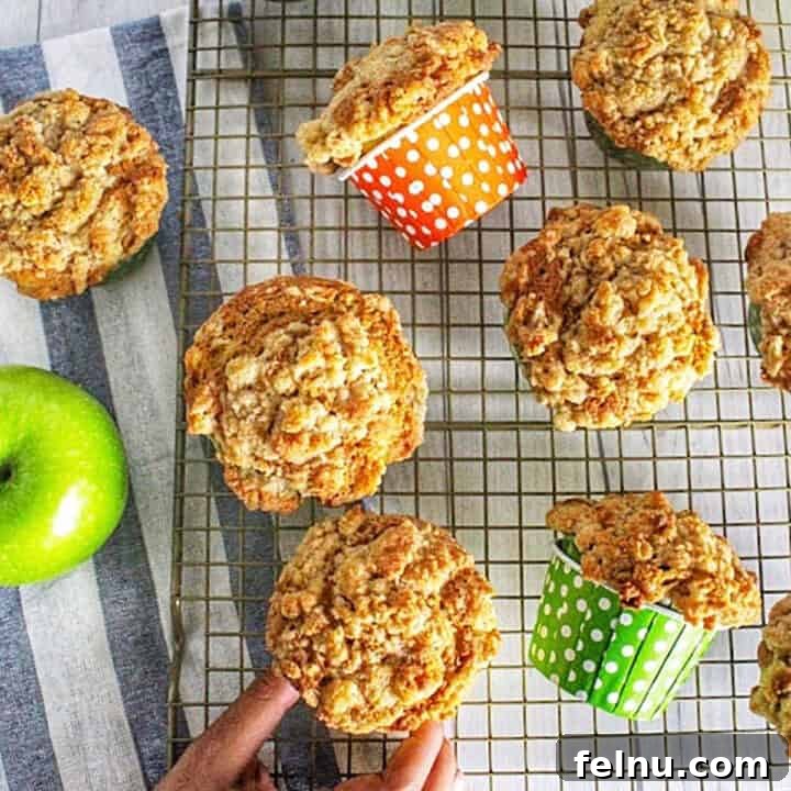Cinnamon Apple Crumble Muffins 7 Several apple vegetable muffins on a cooling rack with one hand taking a muffin.