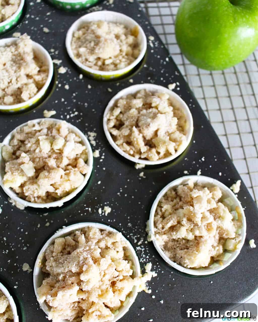 Cinnamon Apple Crumble Muffins 5 Muffin batter filled into a muffin tin, topped with streusel, ready for baking.