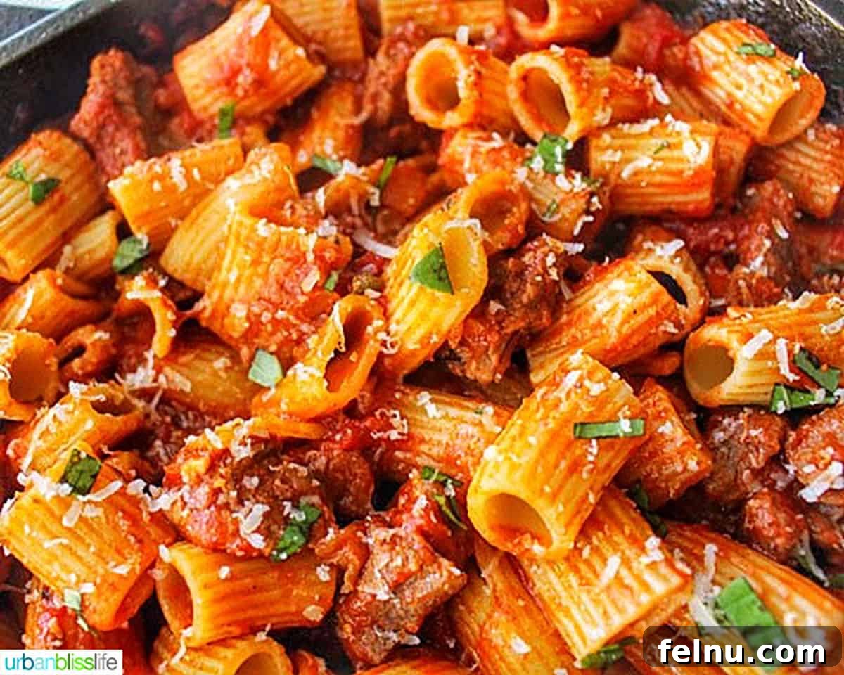Effortless Italian Sausage Rigatoni Delight 3 A close-up of rigatoni pasta with Italian sausage in a cast iron skillet.
