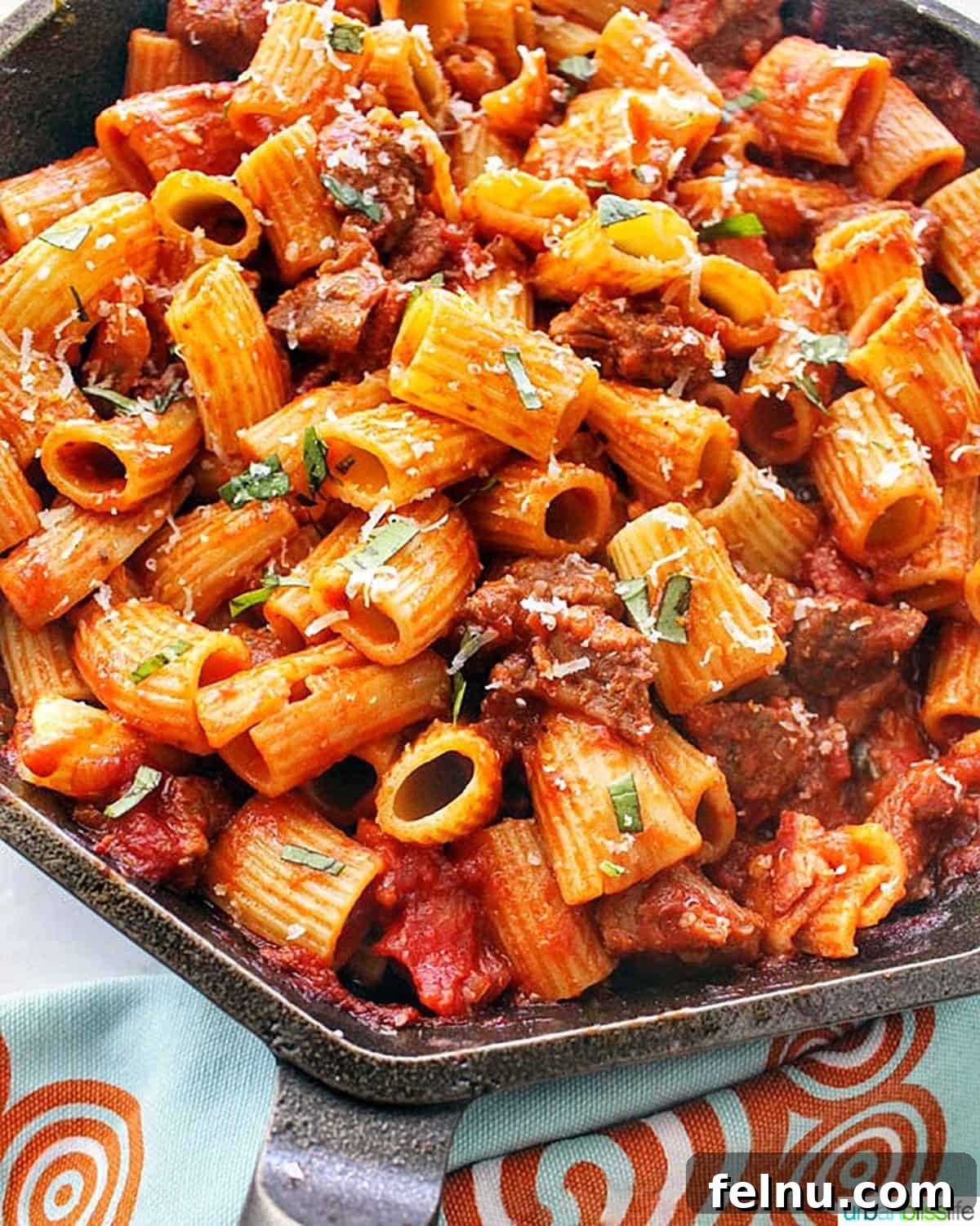 Effortless Italian Sausage Rigatoni Delight 4 An overhead view of rigatoni pasta with Italian sausage in a cast iron skillet.